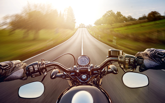 POV shot of young man riding on a motorcycle. Hands of motorcyclist on a street